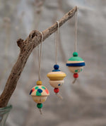 Grapat kind folk wooden Christmas ornaments hanging decorations, three hand painted wooden decorations hung on a branch.