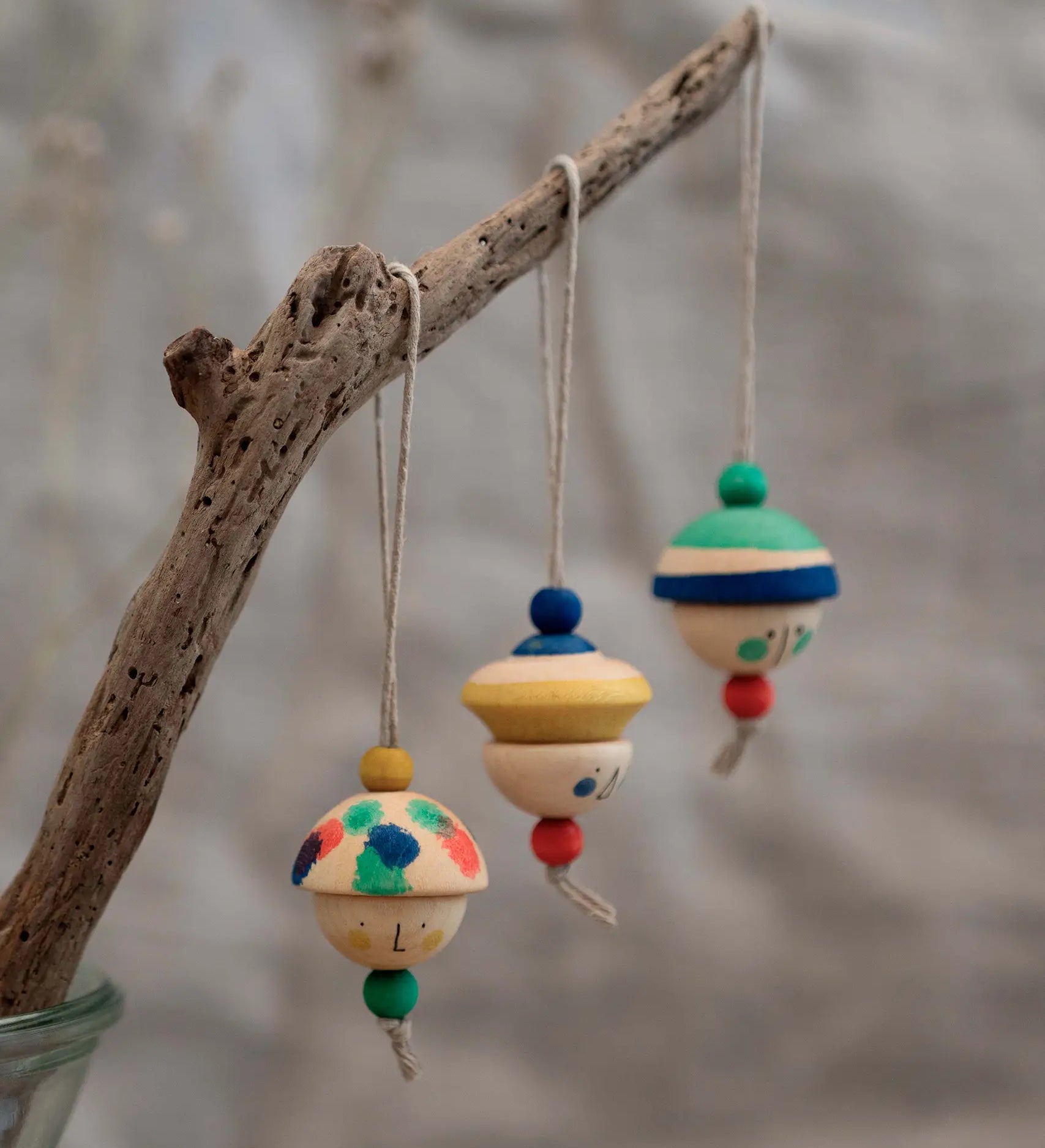 Grapat kind folk wooden Christmas ornaments hanging decorations, three hand painted wooden decorations hung on a branch.