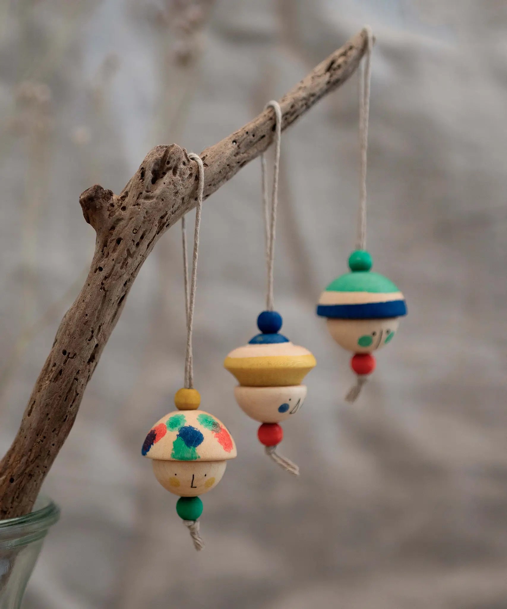 Grapat kind folk wooden Christmas ornaments hanging decorations, three hand painted wooden decorations hung on a branch.