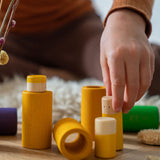 A close up of the yellow pieces from the Grapat Lo wooden toy play set. A set that consists of cylinder and tubes than can be slotted in or on top of each other. These wooden toys are part of a wide range of open ended toys available at Babipur.