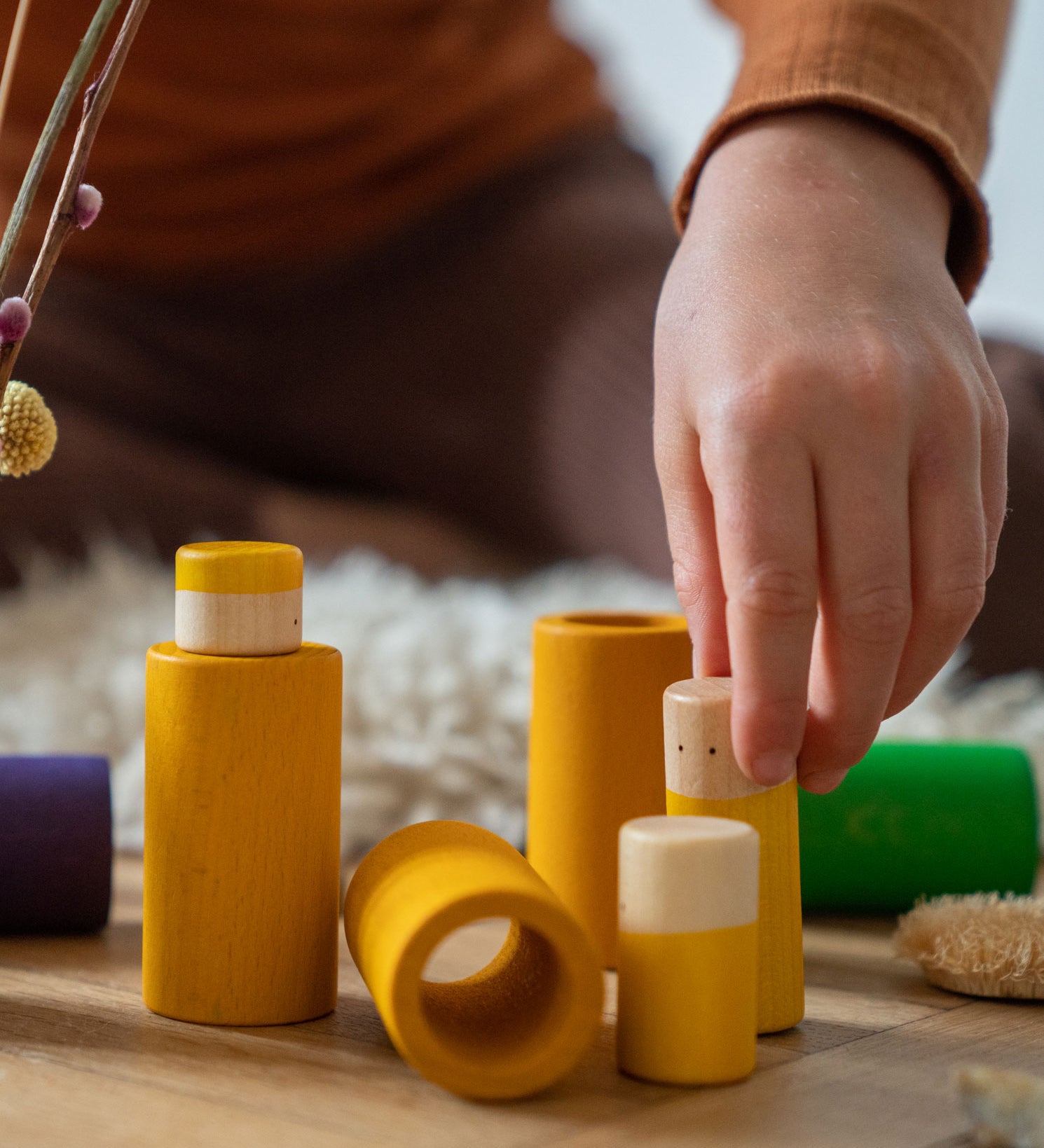 A close up of the yellow pieces from the Grapat Lo wooden toy play set. A set that consists of cylinder and tubes than can be slotted in or on top of each other. These wooden toys are part of a wide range of open ended toys available at Babipur.