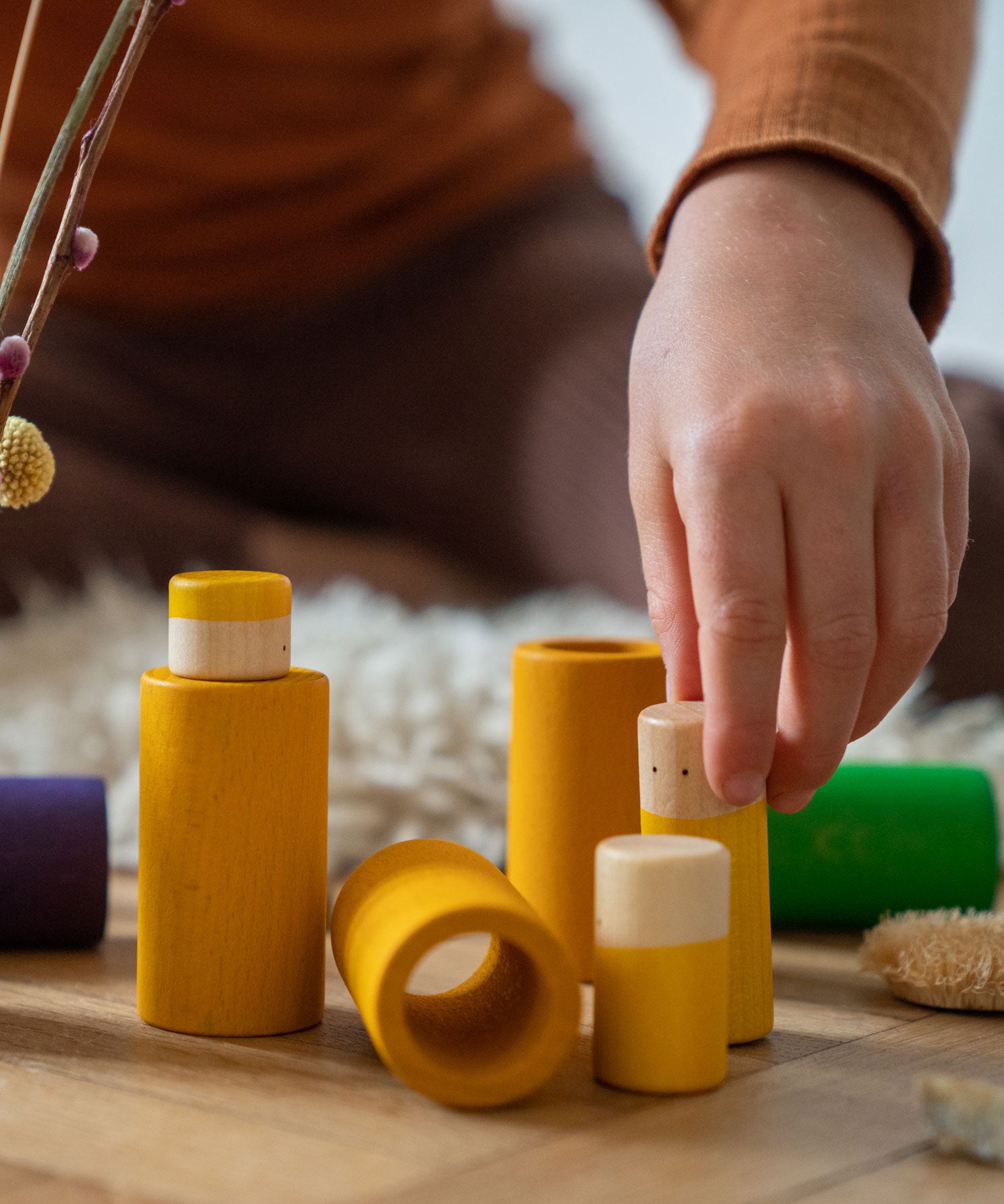 A close up of the yellow pieces from the Grapat Lo wooden toy play set. A set that consists of cylinder and tubes than can be slotted in or on top of each other. These wooden toys are part of a wide range of open ended toys available at Babipur.