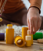 A close up of the yellow pieces from the Grapat Lo wooden toy play set. A set that consists of cylinder and tubes than can be slotted in or on top of each other. These wooden toys are part of a wide range of open ended toys available at Babipur.