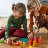Children playing with the Grapat Lo wooden toy play set. A set that consists of cylinder and tubes than can be slotted in or on top of each other. These wooden toys are part of a wide range of open ended toys available at Babipur.