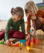 Children playing with the Grapat Lo wooden toy play set. A set that consists of cylinder and tubes than can be slotted in or on top of each other. These wooden toys are part of a wide range of open ended toys available at Babipur.