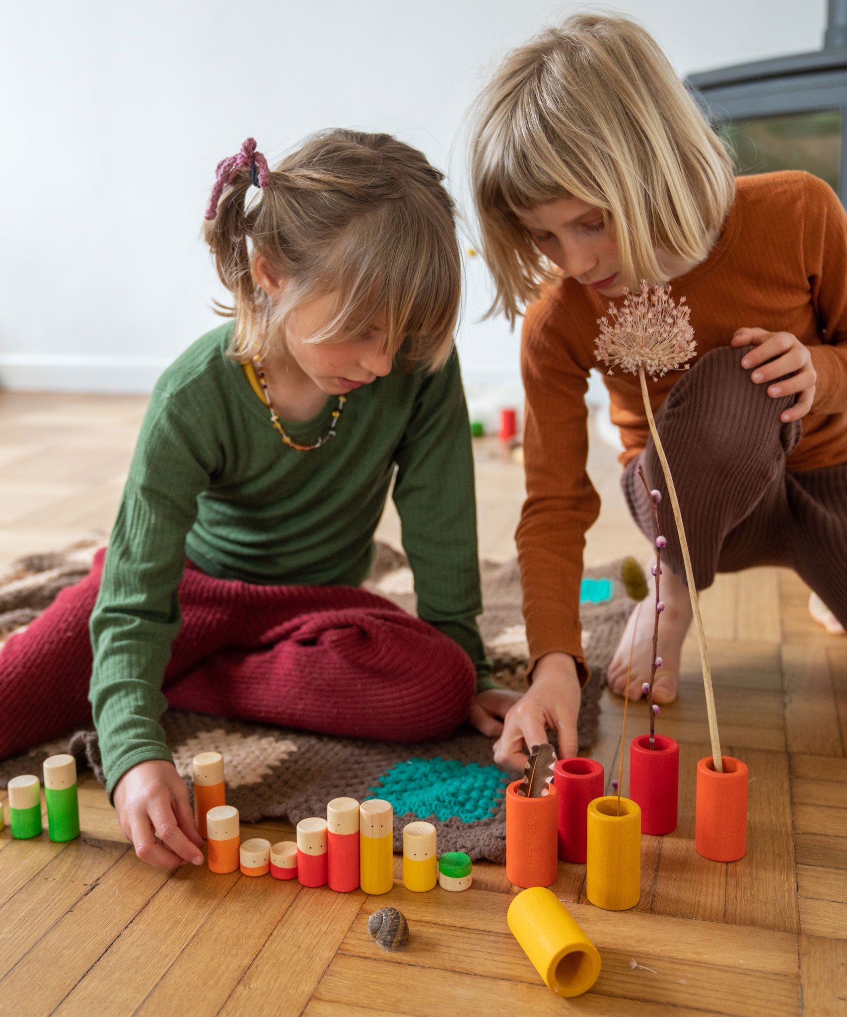 Children playing with the Grapat Lo wooden toy play set. A set that consists of cylinder and tubes than can be slotted in or on top of each other. These wooden toys are part of a wide range of open ended toys available at Babipur.