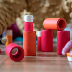 Close up of child's hands stacking the Grapat wooden Lo toy set on a wooden floor