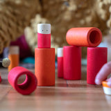 Close up of child's hands stacking the Grapat wooden Lo toy set on a wooden floor