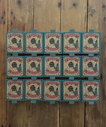 15 boxes of Grapat Lucky Lucky boxes mystery toy boxes lined up on a wooden floor with the surprise wooden toys hidden inside.