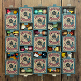 15 boxes of Grapat Lucky Lucky boxes mystery toy boxes lined up and slightly open showing a peek at the wooden toys inside.
