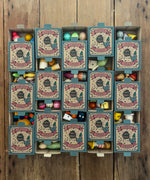 15 boxes of Grapat Lucky Lucky boxes mystery toy boxes lined up and slightly open showing a peek at the wooden toys inside.
