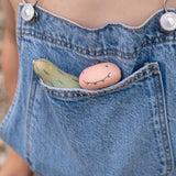 A close up of the wooden monster inspired peg dolls from the Grapat lucky lucky box sitting in a pocket showing the delicate and playful painted detail
