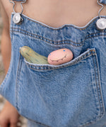 A close up of the wooden monster inspired peg dolls from the Grapat lucky lucky box sitting in a pocket showing the delicate and playful painted detail