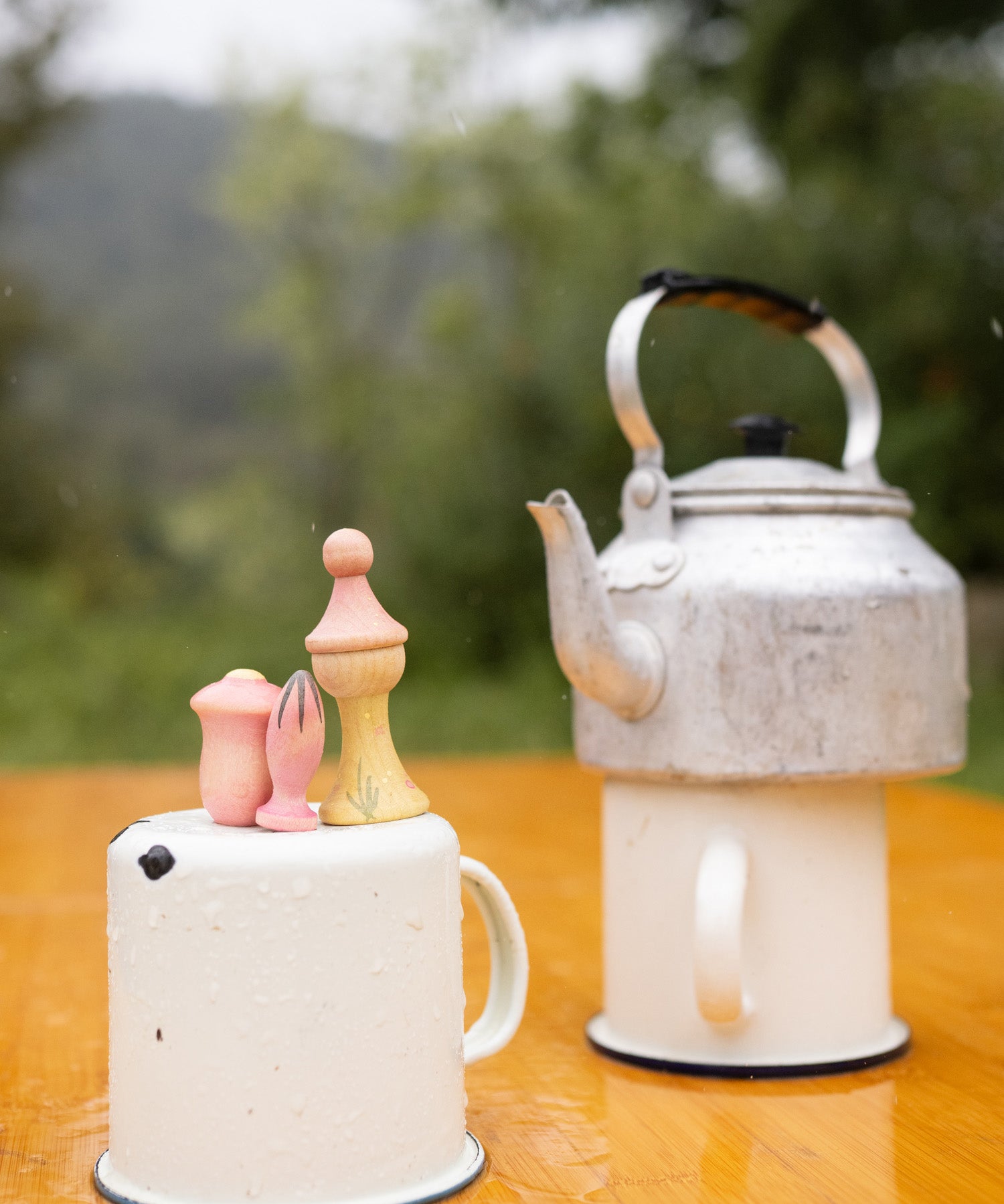 A outdoor picnic setting showing the 3 outdoor inspired wooden peg dolls and pieces from the Grapat lucky lucky boxes. Features delicate and playful hand painted designs. 
