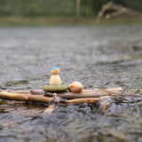 A rainy outdoor setting showing the 3 swimming inspired wooden peg dolls and pieces from the Grapat lucky lucky boxes on a bunch of sticks. 