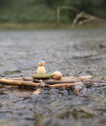 A rainy outdoor setting showing the 3 swimming inspired wooden peg dolls and pieces from the Grapat lucky lucky boxes on a bunch of sticks. 