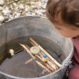 A close up of the 3 swimming inspired wooden peg dolls and pieces from the Grapat lucky lucky boxes in a bucket of water with a homemade raft on the water