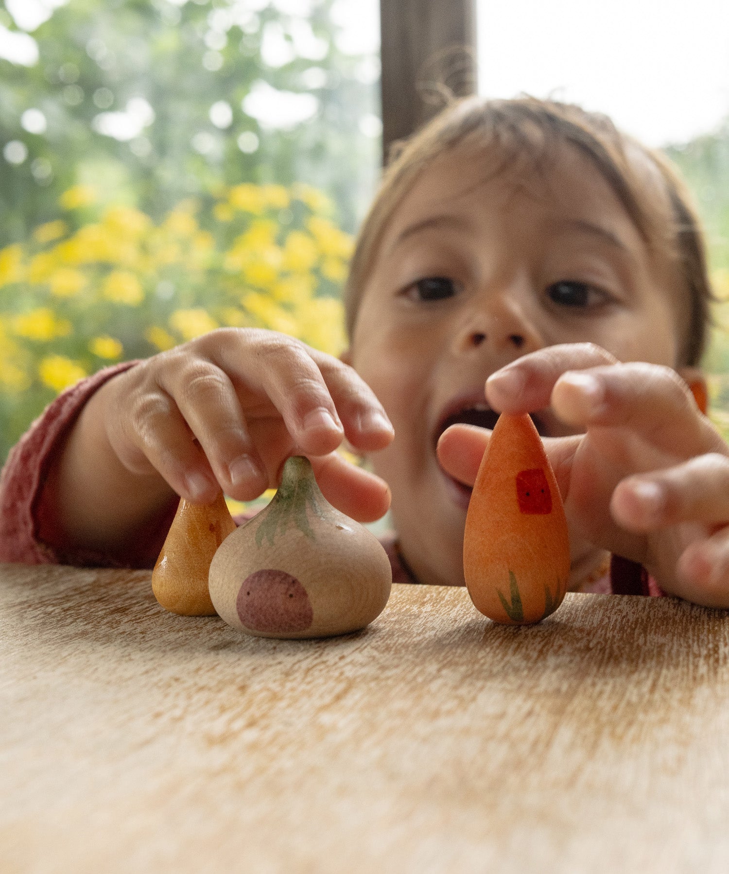 A child playing with the veg inspired wooden peg dolls from the Grapat 4th edition lucky lucky boxes showing the delicate painted detail and scale.