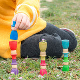 A child stacking the Grapat 12 Magos wooden peg dolls with top hats in a rainbow of 12 colours. These wooden toys are part of a wide range of open ended toys available at Babipur.  