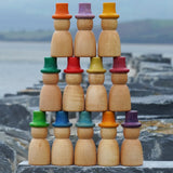 Grapat 12 Magos Rainbow Hats placed on slate outdoors. Natural wooden magos peg dolls with hand-painted rainbow coloured hats.
