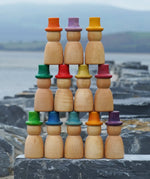 Grapat 12 Magos Rainbow Hats placed on slate outdoors. Natural wooden magos peg dolls with hand-painted rainbow coloured hats.