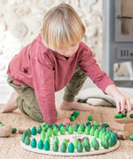 A child playing with the Grapat 36 Mandala Pieces Little Trees. 36 tree shaped mandala pieces in 3 different shades of green, 12 in each colour. Grapat have a wide range of wooden toys and loose parts available at Babipur. 