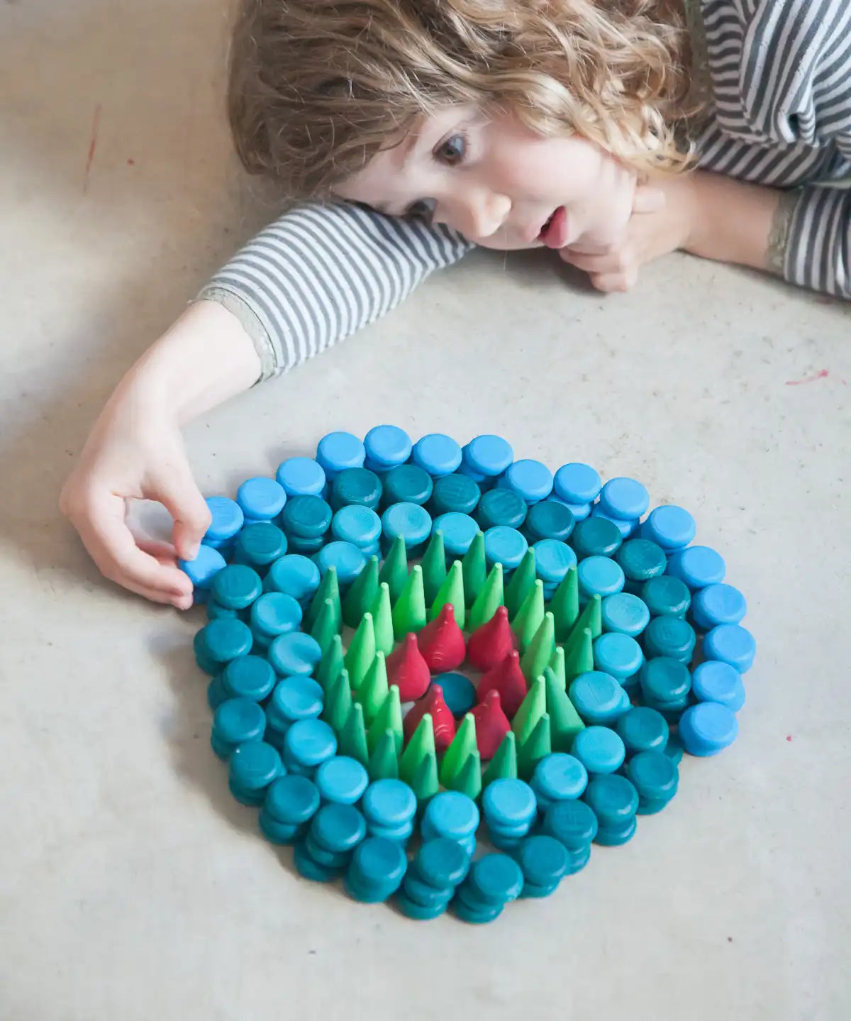 Child creating a mandala with Grapat mandala mini coins.