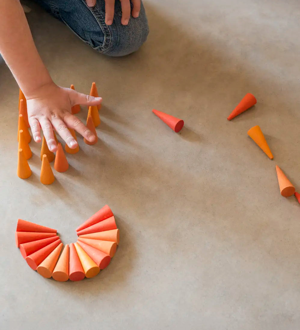 Child playing with the Grapat 36x Mandala Orange Cone wooden pieces.