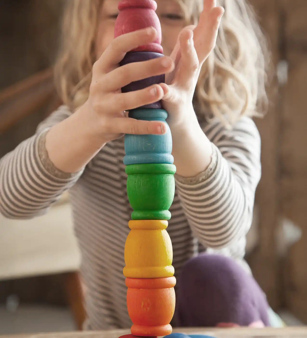 Child stacking Grapat mates rainbow coloured cups on top of each other. 