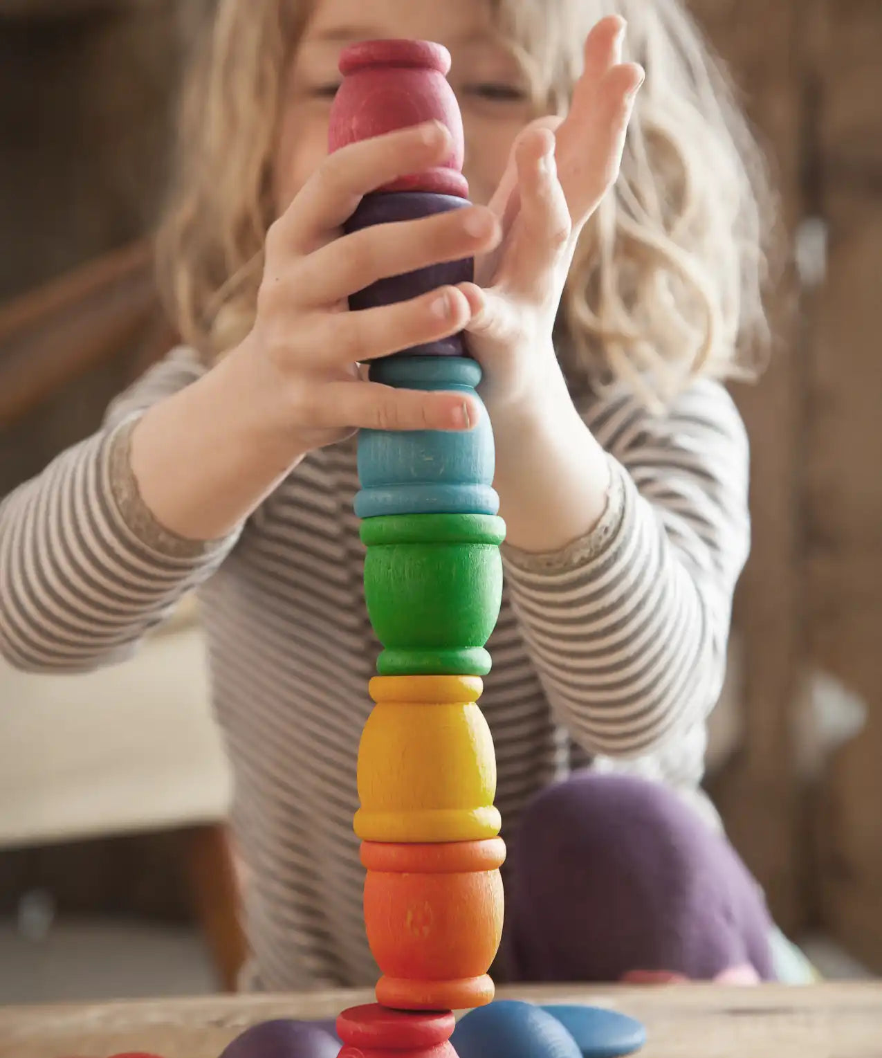 Child stacking Grapat mates rainbow coloured cups on top of each other. 