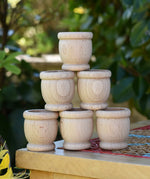 Grapat 6 mates wooden loose parts stacked up on a stool outdoors.
