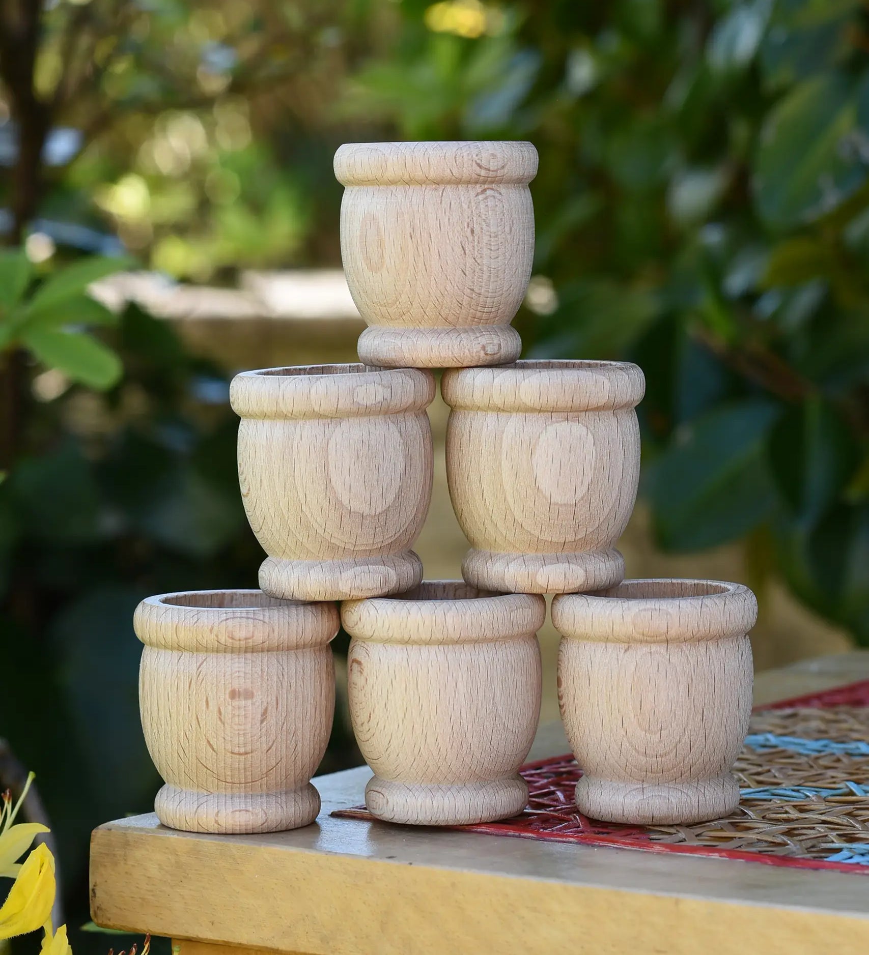 Grapat 6 mates wooden loose parts stacked up on a stool outdoors.