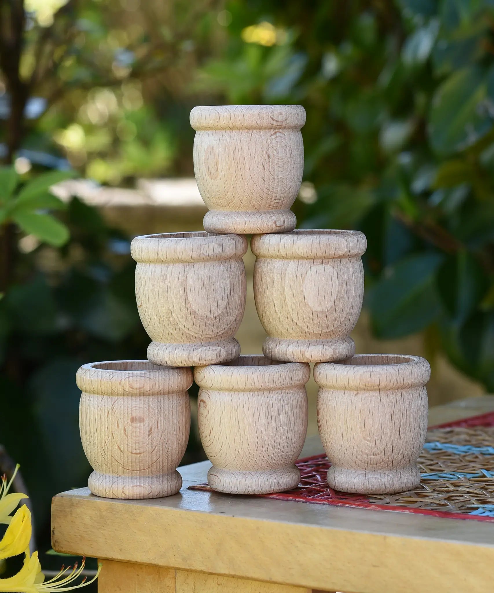 Grapat 6 mates wooden loose parts stacked up on a stool outdoors.