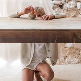 Child playing with the Grapat wooden mellow orange wobble wooden bird on a wooden table showing the hand painted pink and purple detailing. 