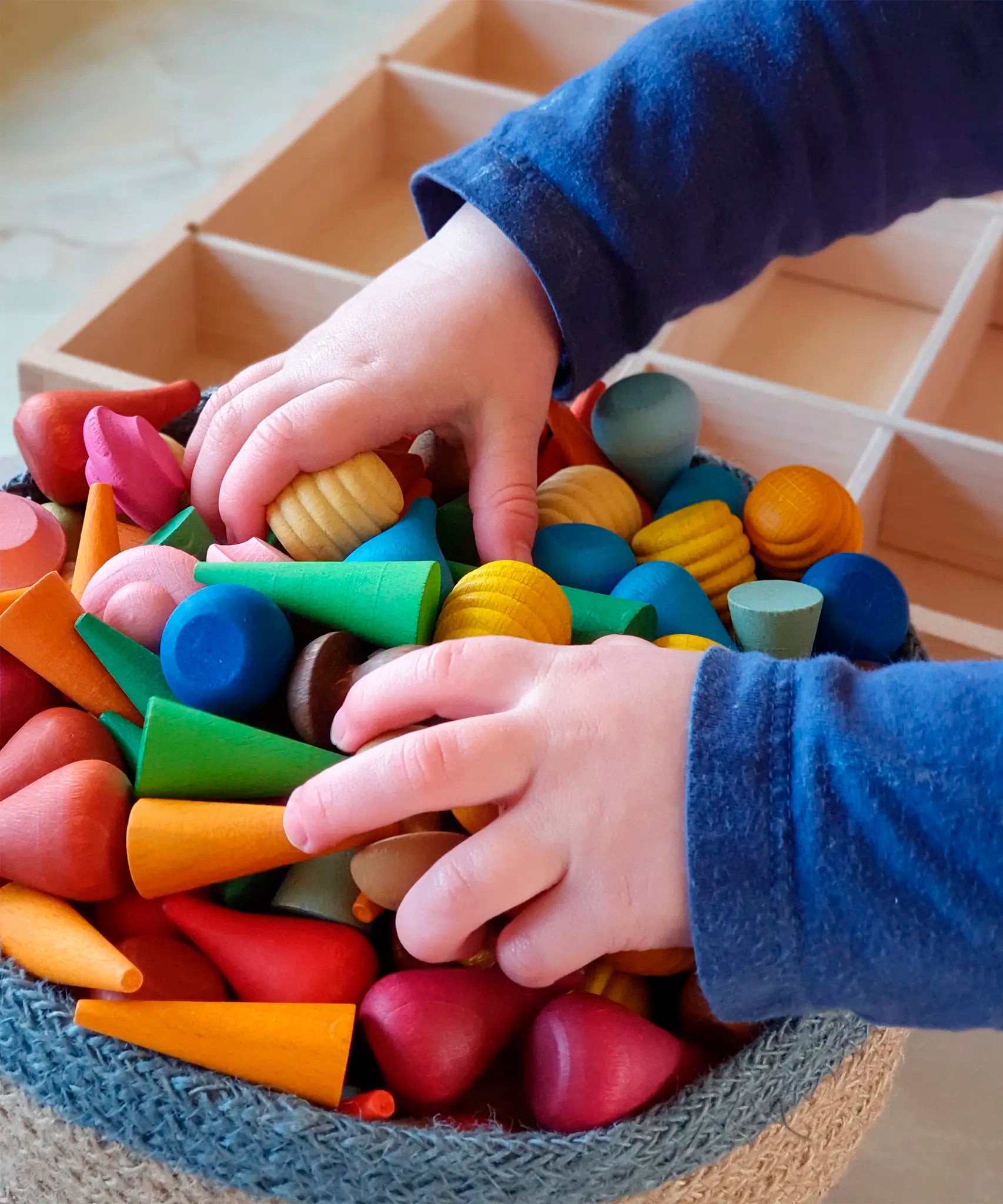 Child holding a bunch of Grapat handcrafted mini wooden mandala pieces in a Respiin basket