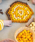 Child sorting Grapat handcrafted mini wooden honeycomb pieces into a pentagon shape on a concrete surface