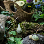 Close up of the Grapat eco-friendly small wooden wild toy set on a log in front of a basket full of flowers