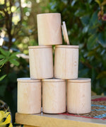 Grapat natural cups with lids stacked up on a stool outdoors. 