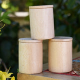 Three Grapat natural cups with lids stacked up on a stool outdoors. 