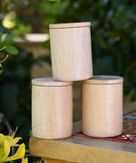 Three Grapat natural cups with lids stacked up on a stool outdoors. 