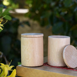 Two Grapat natural cups with lids on a stool outdoors. 