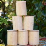 Grapat natural cups with lids stacked up on a stooll outdoors. 