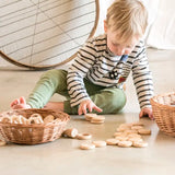 Child playing with Grapat's natural handcrafted wooden disks on a concrete floor