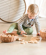 Child playing with Grapat's natural handcrafted wooden disks on a concrete floor