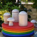 Grapat loose parts, mates, cups mushroom, honeycomb cup placed on a stack of rainbow dishes. 