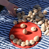 Grapat natural mandala pieces placed on a red dish to create a face.