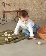 Child playing with a Grapat natural handcrafted wooden ball on a concrete surface