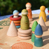 Grapat natural wooden cone placed on a platform with other loose parts and wild crew peg doll Nins. 