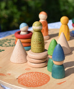 Grapat natural wooden cone placed on a platform with other loose parts and wild crew peg doll Nins. 