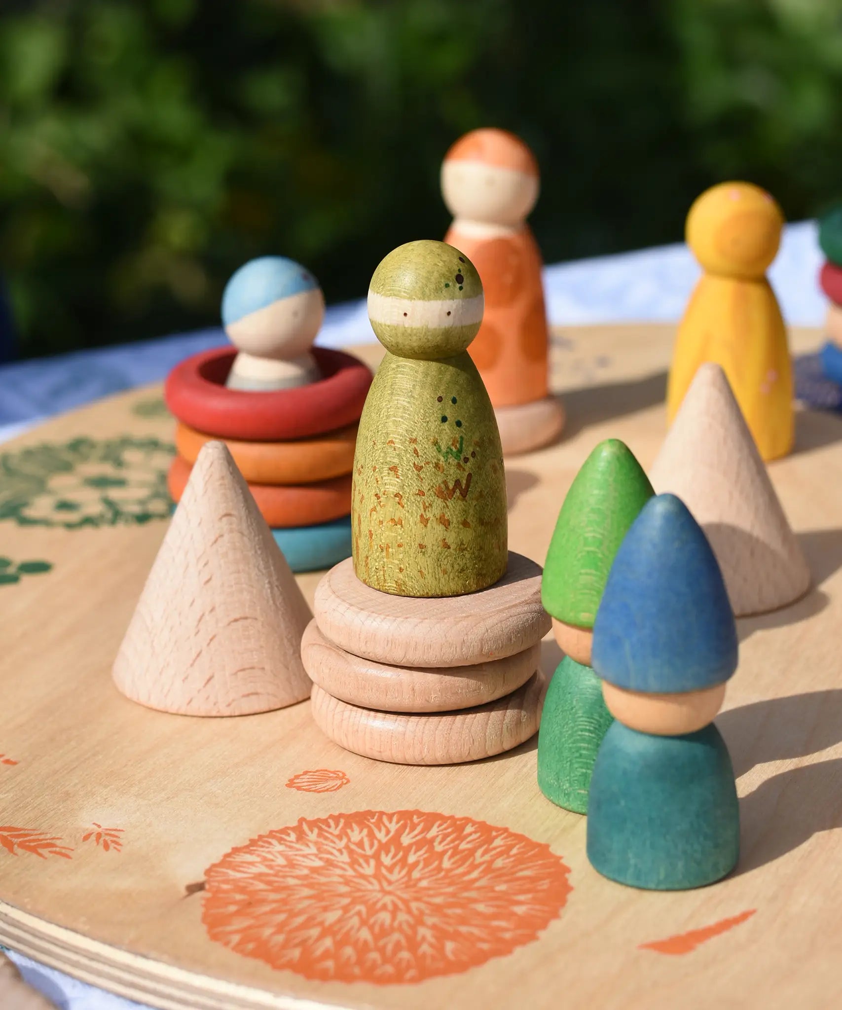 Grapat natural wooden cone placed on a platform with other loose parts and wild crew peg doll Nins. 